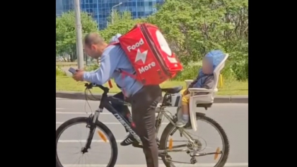 Imagini virale cu un livrator Tazz: filmat cu copilul adormit pe bicicletă