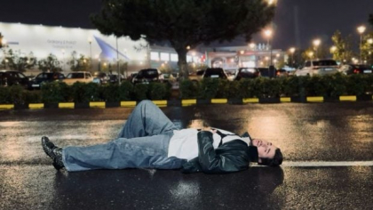 Cine este artistul filmat noaptea întins pe asfalt, în mijlocul ploii: „Scenă de film noir”
